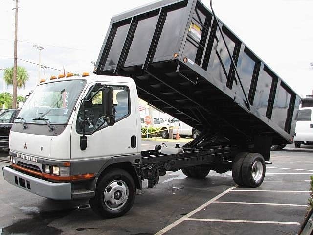 A black and white dump truck parked in a parking lot, likely from a hauling service.